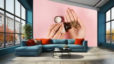 Tablets of dietary supplements in hand for daily pills intake on pink background. Set of zinc pills, antioxidants from aging, lecithin and adaptogen. Wall mural