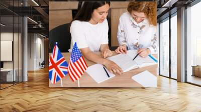 Teacher of english asks student in white class. 2 girls student answers to teacher. Working in group. Study english and british language. Wall mural