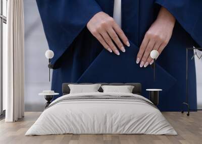 Young female hands holding navy graduation cap, horizontal Wall mural