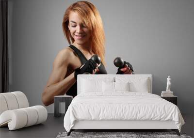 Sporty, muscular female fitness trainer in sportswear posing with dumbbells on a dark background. Wall mural