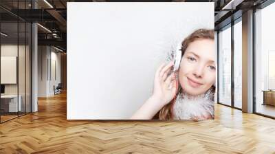 Celebrating New Yea. Young woman with headphones listening to music. Christmas and New Year songs Wall mural