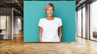 Close up of a 40s middle age woman smiling and wearing a white t-shirt on a turquoise background. Healthy face skin care beauty, skincare cosmetics, dental. Wall mural