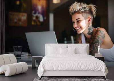 Creative young LGBT woman working on laptop. Girl with tattoo, designer freelancer or student work on computer laptop at table. Wall mural