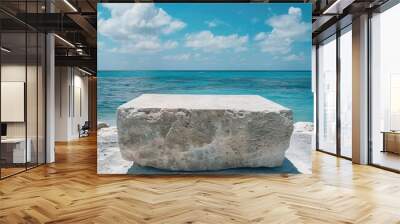 An abstract stone podium sits on a summer beach with a tranquil tropical sea as its backdrop, creating an artistic scene. Wall mural