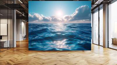 A tranquil sea of aqua blue, dotted with white clouds and basked in the warm embrace of the setting sun, beckons with its calm waves for a peaceful sailing journey through the wonders of nature Wall mural