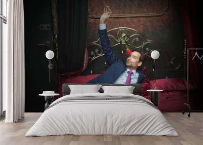 Smiling businessman lying on bed with flower Wall mural