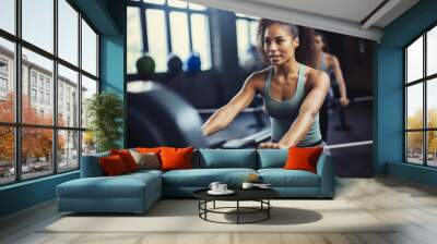 Focused woman training on rowing machine... Wall mural