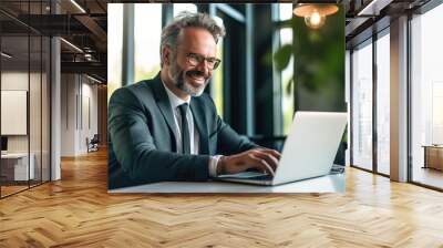 Handsome mature man in suit sitting at the table in home office and working at laptop. AI Generative Wall mural