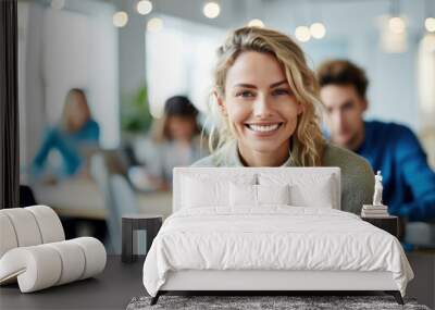 Photo of beautiful happy woman looking at camera while sitting at office Wall mural