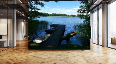 A close up on two colorful kayaks or canoes located next to a wooden pier, marina, or platform situated near some reed formation spotted next to a vast yet shallow river or lake in Poland Wall mural