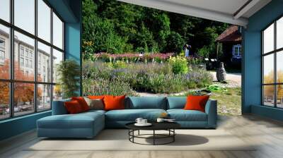 A view of a herbal garden full of herbs, vegetables and other plants ready to be harvested located next to a wooden vintage hut and a dense forest or moor seen on a Polish countryside in summer Wall mural