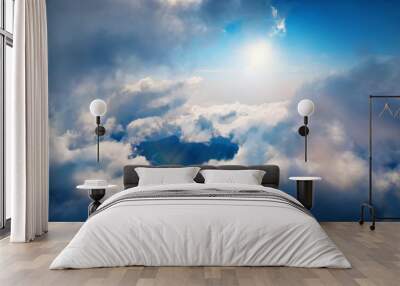 Flying through heavenly beautiful sunny cloudscape. Amazing of white fluffy clouds moving softly on the sky and the sun shining above the clouds with beautiful rays and lens flare. Wall mural