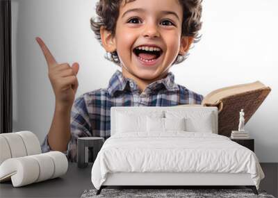 Happy smiling child with curly hair holding a book and pointing up, isolated on white background. Education and learning concept. Wall mural