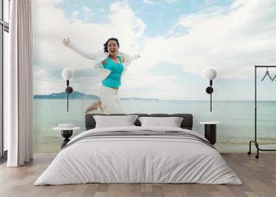 Happy girl jumping on the beach Wall mural