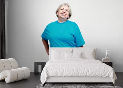 Portrait of a happy senior woman wearing blue tshirt isolated on white background Wall mural