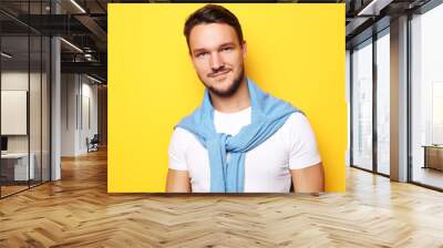 Portrait of a smart young  man standing against yellow backgroun Wall mural