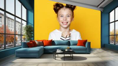 Portrait of cheerful smiling little girl on yellow background  Wall mural