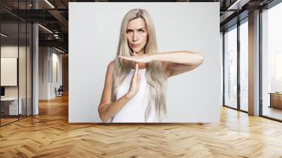 Senior woman with long grey hair making time out sign over grey background Wall mural