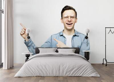 young handsome man smiling cheerfully, feeling happy and pointing to the side and upwards Wall mural