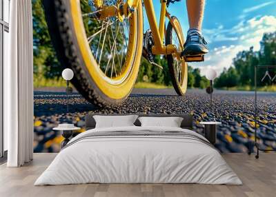 A bright yellow bicycle wheel spins on an asphalt road, full of energy. Wall mural