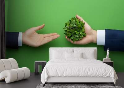 A hand holds green leaves, symbolizing a commitment to sustainability and the earth�s future. Wall mural