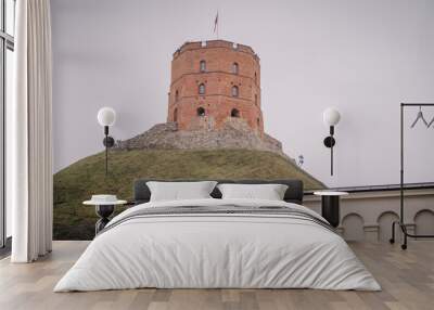 A historic brick tower atop a grassy hill with stone fortifications, under a cloudy sky, featuring an ancient architectural design.. Wall mural