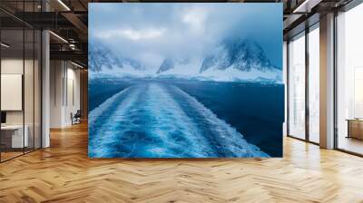 Ship is leaving a wake in the deep blue water of antarctica, with snow-covered mountains and glaciers in the background Wall mural