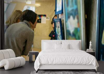 rear view of younga caucasian woman stading in an art gallery in front of two large colorful paintings Wall mural