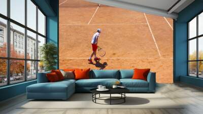 The boy plays tennis on the orange dirt court. Court hard Wall mural