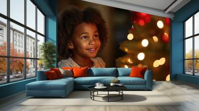 Little girl looking at camera excited smile with Christmas Tree decoration in living room night light, Hispanic child hold beautiful red christmas gift standing in front of family dinner party at home Wall mural