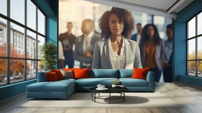 Smiling african American businesswoman standing in front of team of business people working in the office looking camera, executive manager female Afro hair wearing white suit hold notebook technology Wall mural