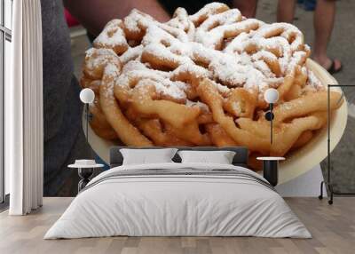 A hand holding a plate of funnel cake with powdered sugar on top Wall mural