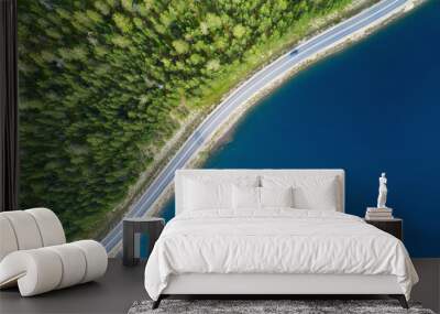 Beautiful aerial view of road between green summer forest and blue lake in Lapland. Car moving on road. Wall mural