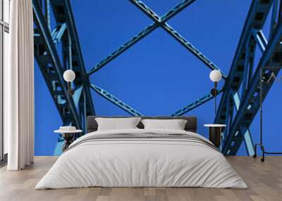 Low angle view on isolated symmetrical industrial steel bridge deck against blue sky with cross struts and metal beams Wall mural