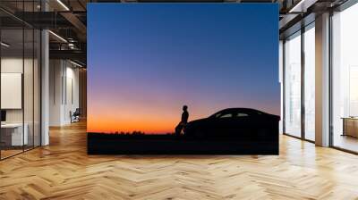 Silhouette of a man and a car on a background of a very beautiful sunset. Freedom and travel by car concept. Wall mural