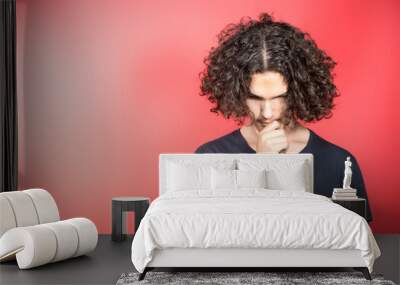 Portrait Of Serious Teenage Boy Standing Against Red Background Wall mural