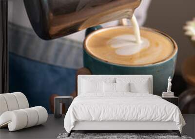 a barista drawing a heart in a mug with espresso and hot milk Wall mural