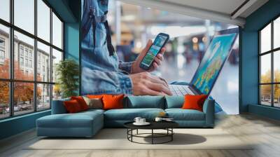 Man using a laptop and smartphone for booking hotel online. Sitting in an airport. Tour reservation, Booking online concept. Wall mural