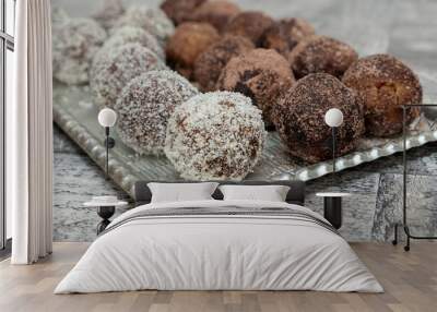 Coconut rum balls being covered with grated coconut on plate Wall mural