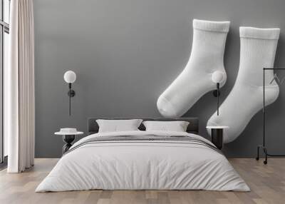 A pair of clean white socks placed on a smooth gray surface, emphasizing simplicity and everyday essentials. Wall mural