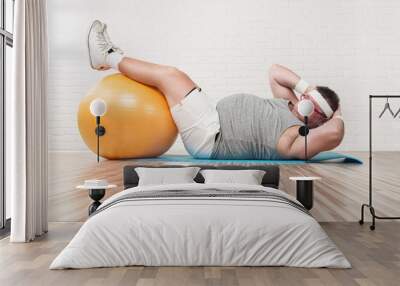 Funny overweight man working out in the gym Wall mural