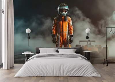 A racing driver in an orange and white suit with a helmet stands on the asphalt Wall mural