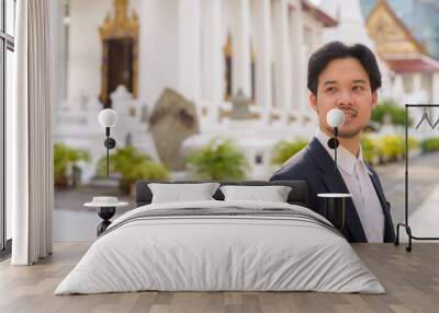 Asian businessman relaxing outdoors in the city at Buddhist temple Wall mural