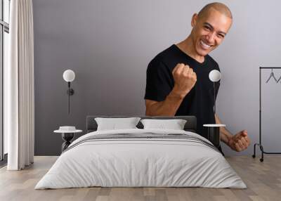 Handsome happy bald man smiling with arm raised Wall mural