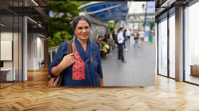 Mature beautiful Indian woman smiling in city Wall mural