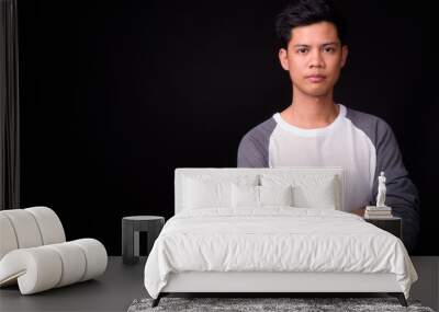 Portrait of young Asian man against black background Wall mural