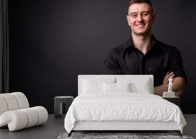 Portrait of young confident businessman smiling with arms crossed looking at camera Wall mural