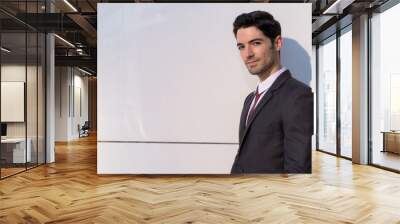 Portrait of young handsome businessman wearing suit in city Wall mural