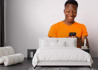 Portrait of young happy African man using phone Wall mural