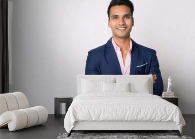 Portrait of young happy Indian businessman in suit smiling with arms crossed Wall mural